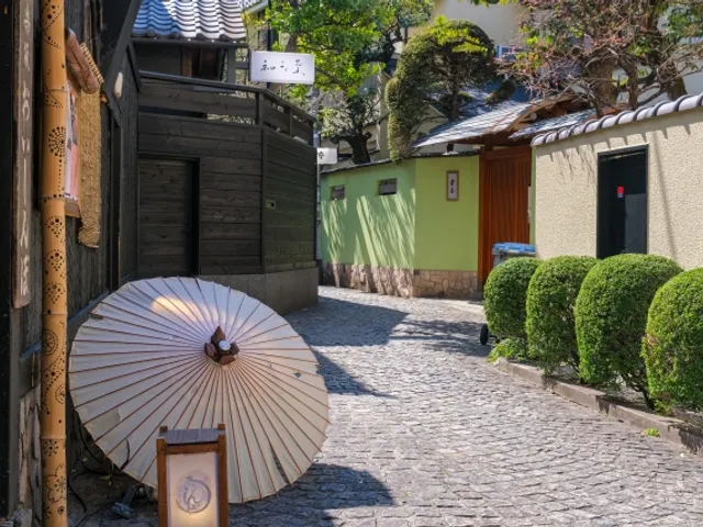 A cobbled side lane in Kagurazaka with a paper parasol outside a restaurant — the stone paving that makes a carrier easier than a stroller