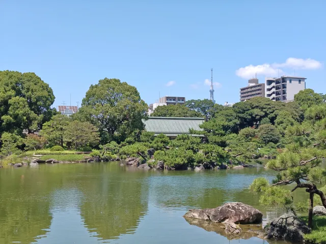 The pond and pines of Kiyosumi Gardens with Tokyo Skytree visible beyond, in Koto, Tokyo