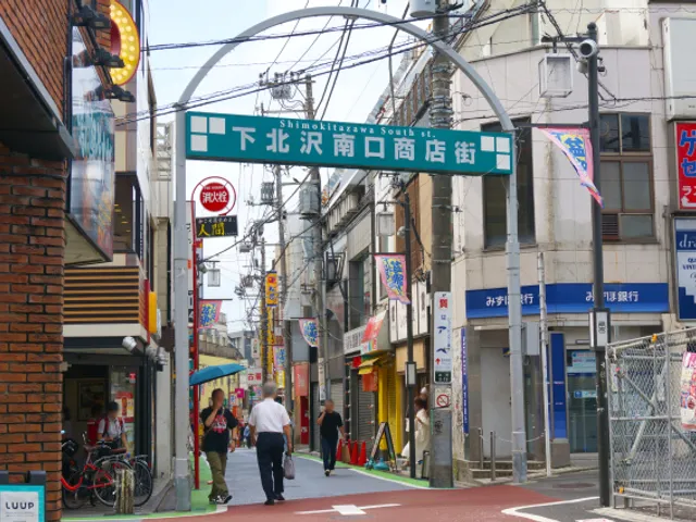 The narrow South Exit shopping street of Shimokitazawa, with its arch sign and no pavements, in Setagaya, Tokyo
